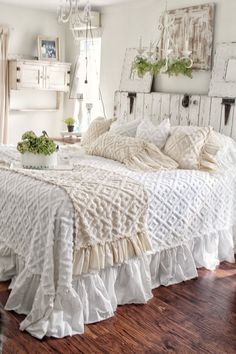 a white bed with ruffled bedspread and pillows on top of it in a bedroom