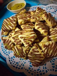 a plate full of cookies with chocolate drizzled on them next to a bowl of sprinkles