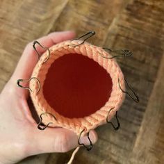 a person is holding an object in their hand on a wooden table with some string attached to it