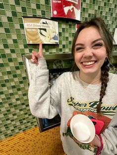 a girl is smiling and holding a coffee cup