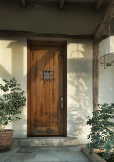 a wooden door with two potted plants in front of it