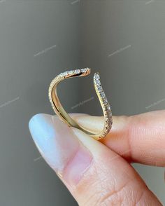 a person holding a gold ring with diamonds on it's side and the top half of their finger