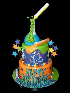 a colorful birthday cake with a science theme on it's bottom tier and stars around the edges