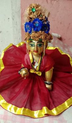 a figurine sitting on top of a table wearing a red and yellow dress