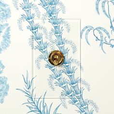 a blue and white floral wallpaper with a gold button on the front of it