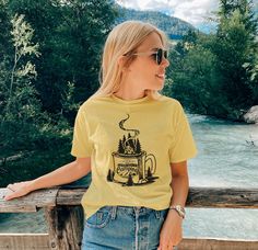 Mug in a camping scene with a tent, mountains, forest, waterfall and campfire. This t-shirt is everything you've dreamed of and more. It feels soft and lightweight, with the right amount of stretch. It's comfortable and flattering for all.  *For oversized, relaxed look, size up to your preference. For the actual sizing, refer to the size chart. * 100% combed and ring-spun cotton (Heather colors contain polyester) * Fabric weight: 4.2 oz/yd² (142 g/m²) * Pre-shrunk fabric * Side-seamed construction * Shoulder-to-shoulder taping * Blank product sourced from Guatemala, Nicaragua, Mexico, Honduras, or the US This product is made especially for you as soon as you place an order, which is why it takes us a bit longer to deliver it to you. Making products on demand instead of in bulk helps reduce Casual Graphic Print Camp Shirt For Hiking, Pre-shrunk Camp Shirt For Summer Outdoors, Casual Graphic Print Camp Shirt, Summer Shirt With Screen Print For Outdoor Activities, Summer Graphic Print Shirt For Hiking, Summer Outdoor Shirt With Screen Print, Casual Summer Camp Shirt For Hiking, Summer Graphic Print Shirt For Outdoor, Casual Pre-shrunk Camp Shirt For Camping