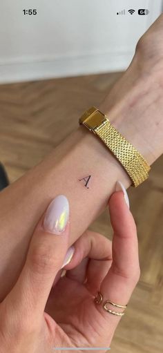 a woman's arm with a gold bracelet on her wrist and the word i tattooed on it