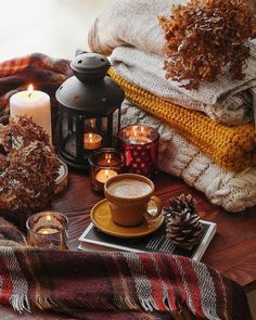 a table topped with candles and blankets next to a cup of hot chocolate on top of a plate