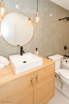 a bathroom with a sink, toilet and bathtub in the background is a herringbone tile wall