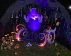 an inflatable octopus is lit up with purple lights and decorations on the ground