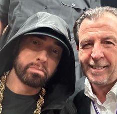 two men are posing for the camera with one wearing a hoodie and the other in a black jacket