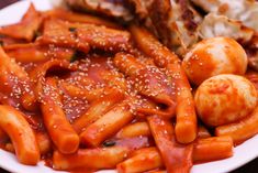 a white plate topped with pasta and meat covered in marinara sauce next to other food items