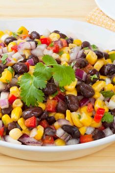 a white bowl filled with black beans, corn and cilantro garnish