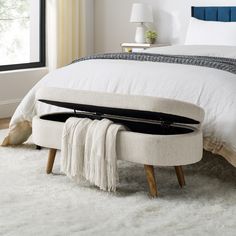 a white bed with a blue headboard and footstool on top of it