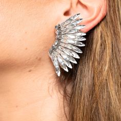 Add a touch of elegance and sophistication to your look with our stunning Silver Crystal Wing Earrings! These exquisite statement earrings feature a shimmering silver crystal stud and a unique winged design, perfect for any occasion. Handmade with attention to detail, these earrings exude quality and beauty. Lightweight and comfortable, they are perfect for all-day wear. Elevate your style and feel confident with our exceptional Silver Crystal Wing Earrings! Size: Length: 2.25''/ Width: 1.75'' Sparkling Sterling Silver Crystal Earrings For Party, Dazzling Sterling Silver Crystal Earrings For Party, Elegant Winged Metal Jewelry, Dazzling Single Crystal Earring For Parties, Glamorous Silver Clip-on Earrings With Rhinestones, Sparkling Silver Clip-on Earrings For Evening, Sterling Silver Crystal Earrings For Party, Glamorous Silver Crystal Earrings For Gift, Silver Winged Sterling Silver Earrings