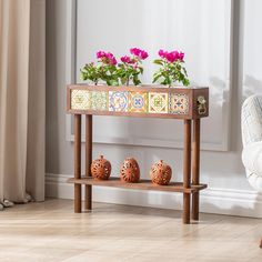 two vases with flowers are sitting on a wooden shelf in front of a window