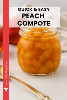 a jar filled with peach compote sitting on top of a table next to a spoon