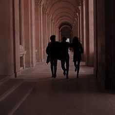 two people walking down an alley way in the dark with their backs turned to the camera