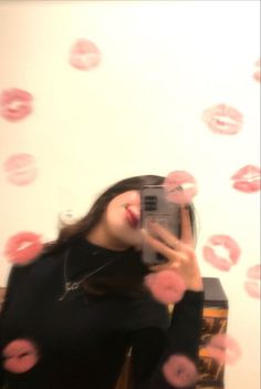 a woman taking a selfie in front of a mirror with pink donuts flying around her