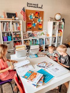 two children sitting at a table with books