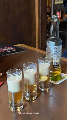 there are three glasses and two bottles on the table with drinks in front of them