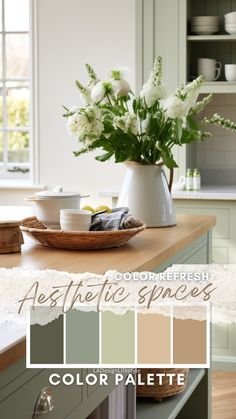 the color scheme for this kitchen is pale green and has white flowers in a vase