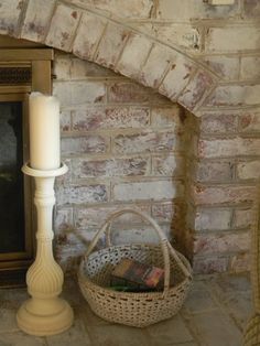 a white candle sitting on top of a table next to a basket with books in it