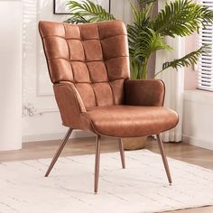 a brown chair sitting on top of a white rug next to a potted plant