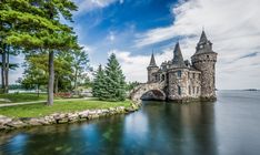 a castle sitting on top of a lake next to a forest