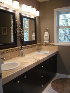 a bathroom with double sinks and two mirrors