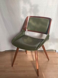 a green chair sitting on top of a hard wood floor next to a white wall