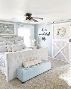 a bedroom with a white bed, blue and gray decor and an open barn door