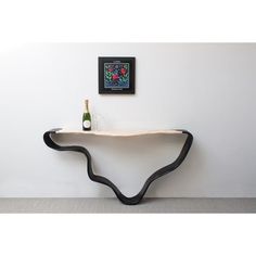 a white table with black curved legs and a bottle of wine sitting on top of it