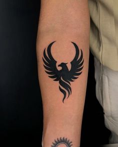 a tattoo on the arm of a man with an eagle and sun design in black ink