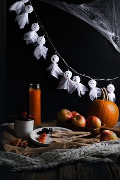 a table topped with lots of different types of food next to a string of ghost decorations