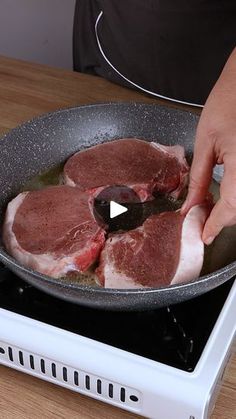 a person cooking meat in a frying pan on top of an electric stovetop