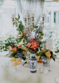 an arrangement of flowers in vases and candles on a table at a wedding reception