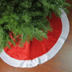 there is a red and white christmas tree skirt on top of the table with green branches