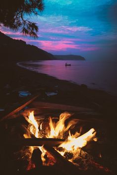 a campfire is lit up at night on the beach