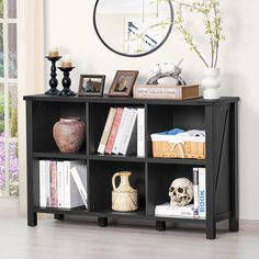 a black book shelf with books and vases on it in front of a window