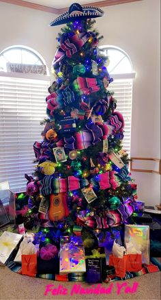 a brightly lit christmas tree with lots of presents on it's bottom and sides