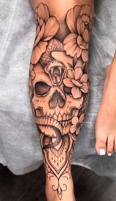 a woman's leg with flowers and a skull on the bottom half of it