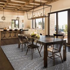 a large open kitchen and dining room area with wood beams on the ceiling, tile flooring and wooden chairs