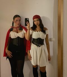 two women dressed in costumes standing next to each other and taking a selfie with their cell phones