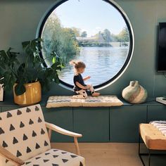 a little boy sitting on a window sill in front of a large round window