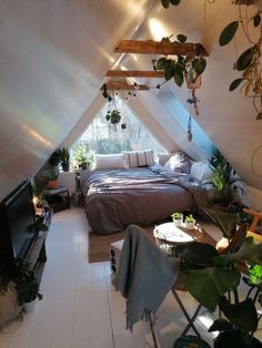 an attic bedroom with a bed, desk and television