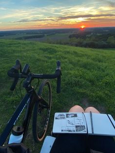 a bicycle parked next to a person laying on the ground with a book in front of them