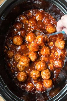 someone is spooning meatballs out of the slow cooker with sauce on it