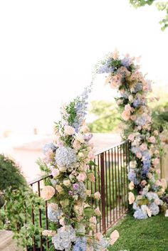 an outdoor ceremony with flowers and greenery on the fenced in area next to it