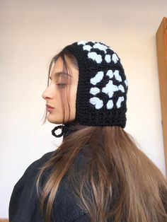 a woman with long hair wearing a black and white crocheted beanie hat